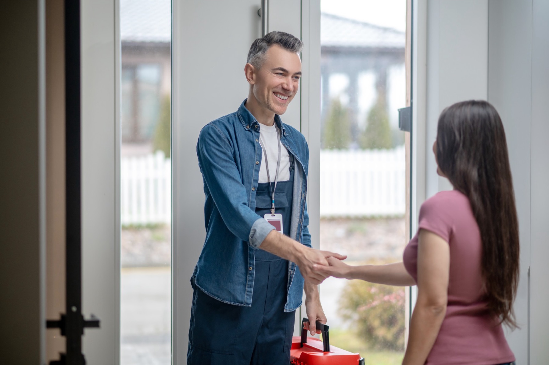 Un technicien VEENT serre la main d’une cliente sur le pas de sa porte